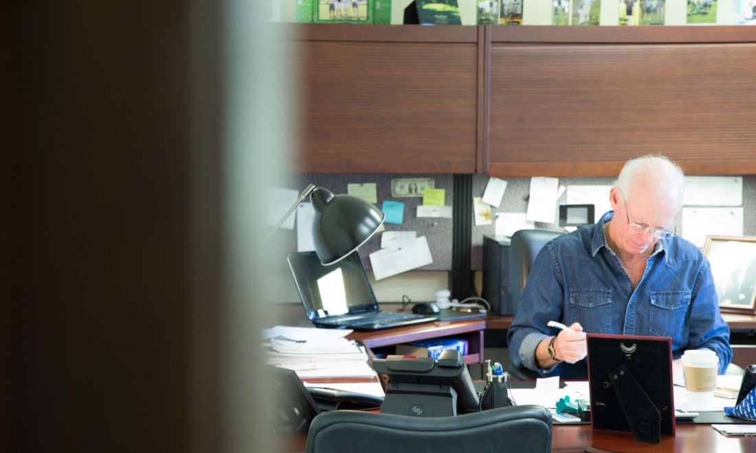 Brian O'Brien working on papers at his desk in his office.