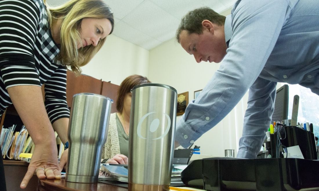 team members working together at a desk with an O'Brien thermos in the center that has the O'Brien O logo