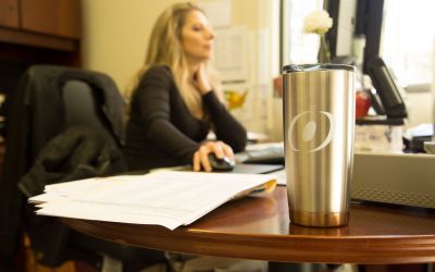 a female O'Brien employee working at her desk with an O'Brien thermos in front of her