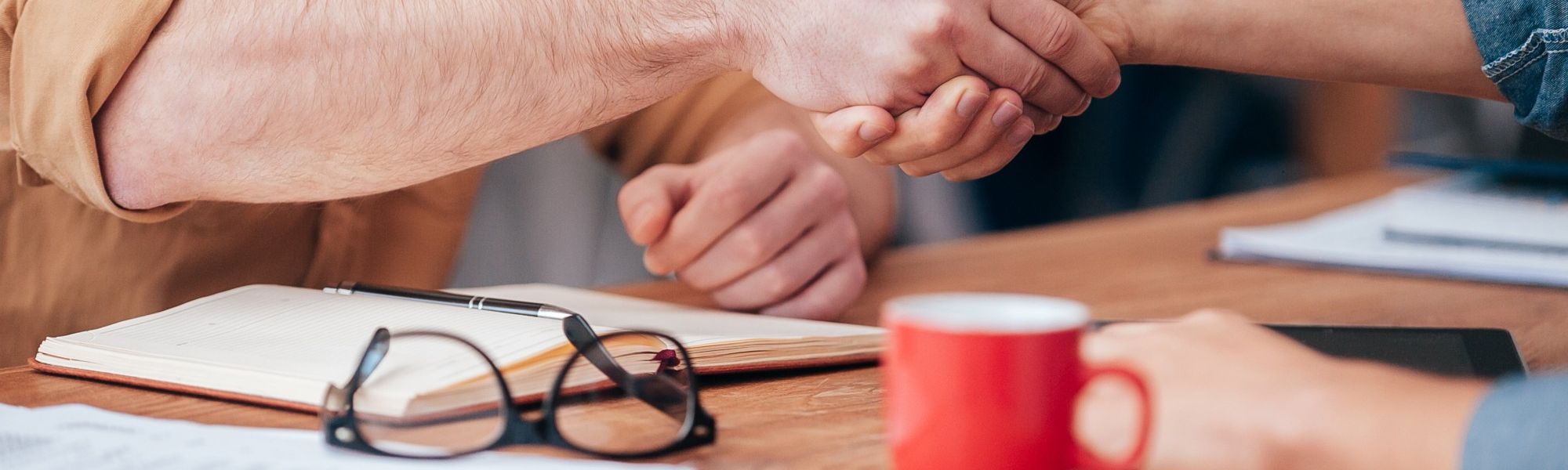 Two people shaking hands at a conference table 